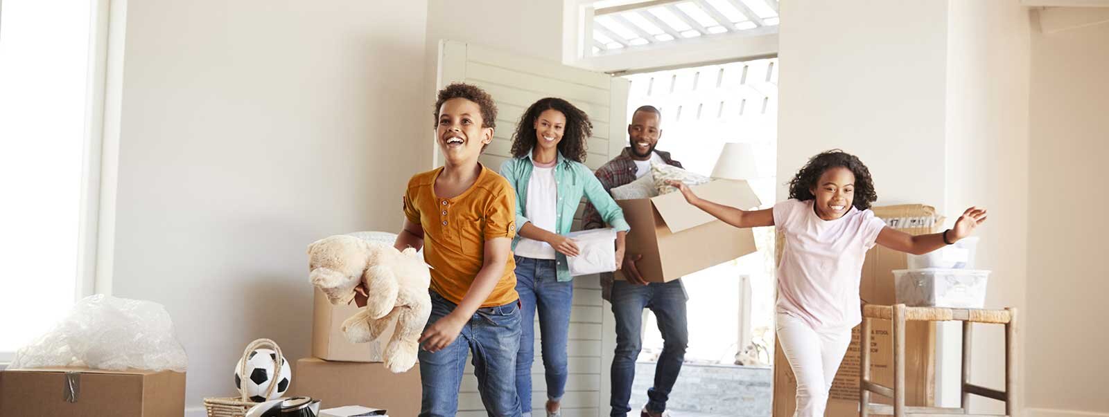 Family carrying boxes and moving into new home